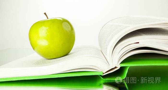 在书背景下关闭新鲜的绿色苹果