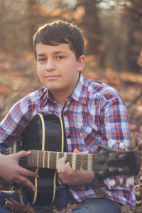 十几岁的男孩在阳光明媚的秋日的吉他