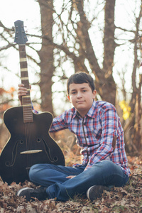 十几岁的男孩在阳光明媚的秋日的吉他