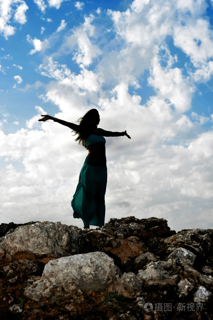 户外张开双臂的年轻迷人女人的剪影