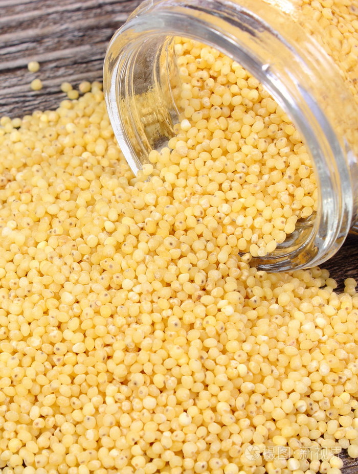 谷子去壳溢了出来,玻璃罐.木制的背景