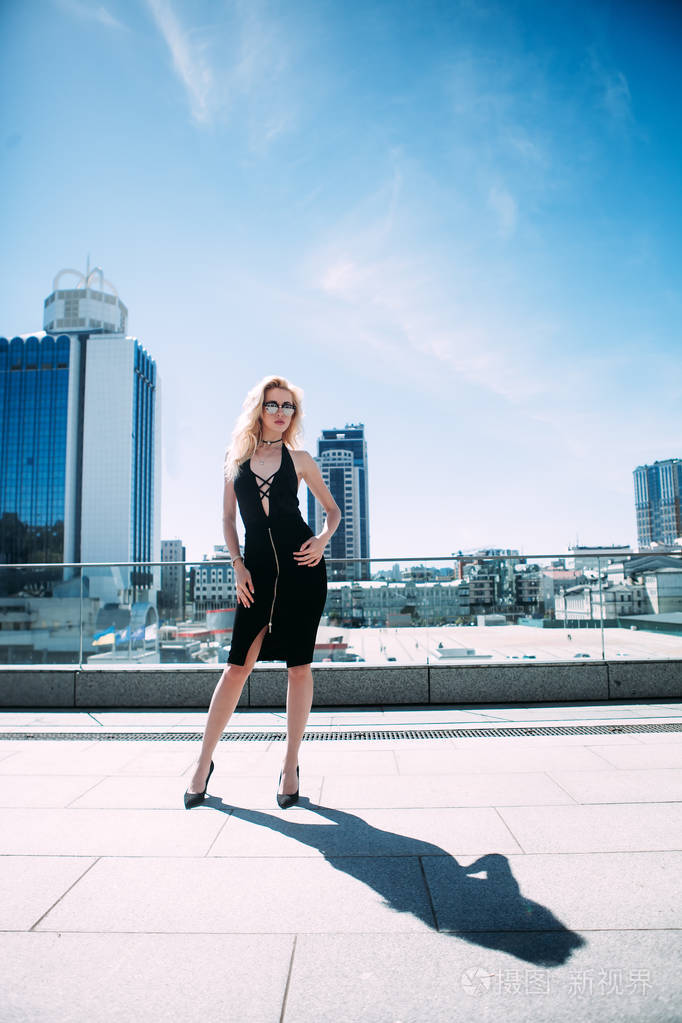 户外全身画像的年轻时尚美女在大街上摆姿势.看着摄像机的模型.