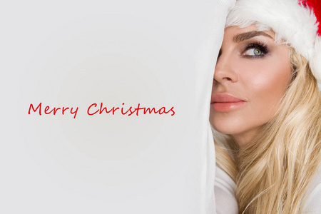 美丽的金发碧眼女模特打扮成圣诞老人，在一顶红帽子与在白色的皮毛可爱化妆的嘴唇，圣诞节