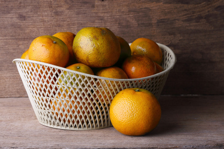 在木桌背景上的白色篮子橙色水果