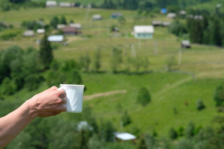 手与白杯咖啡山背景