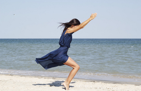 做瑜伽在海边穿着蓝色衣服的年轻美丽的女人