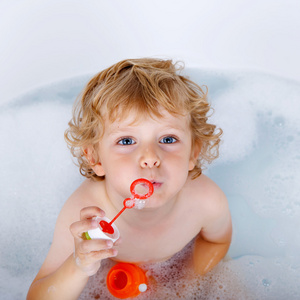 蹒跚学步男孩玩肥皂泡泡在浴缸里