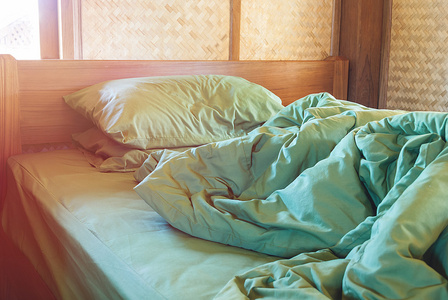 绿色枕头和毛毯，在老式床上凌乱窝