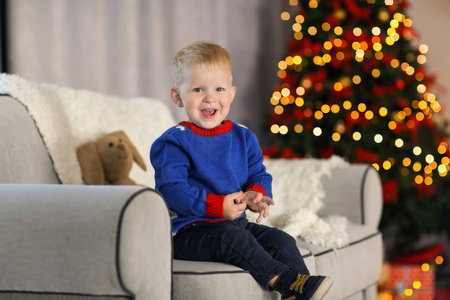 可爱的小男孩，坐在沙发上在为圣诞房间装饰