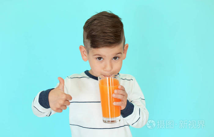 可爱的小男孩在彩色背景上喝果汁