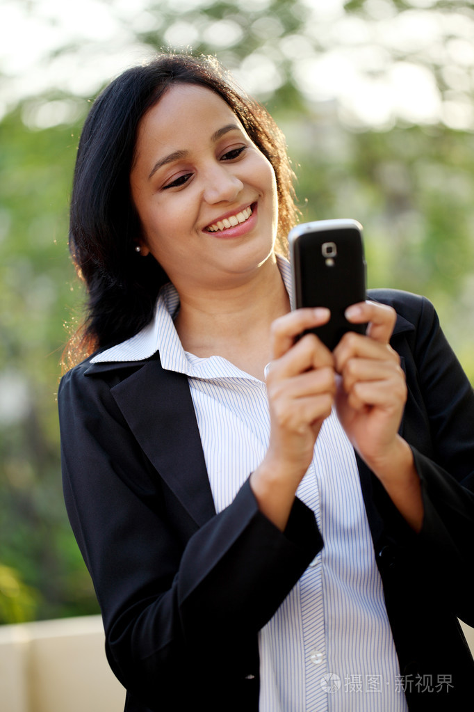 愉快的年轻商业女人发短信在户外活动