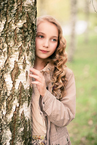 肖像的漂亮的女孩站在靠近树