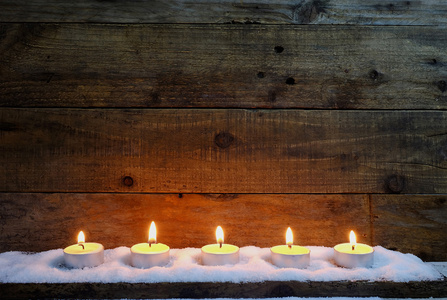 蜡烛在木制背景与雪上
