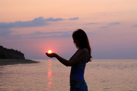 在她的手掌举行太阳的女人剪影