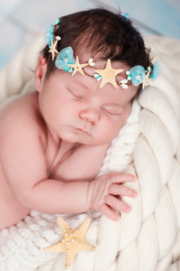 密切的一个熟睡的新生女孩在海事箍的海星和珍珠的肖像