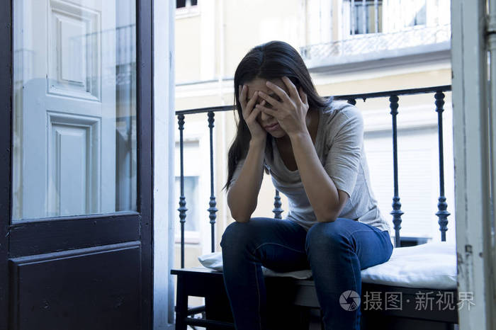 绝望的拉丁女人坐在家里的阳台上被毁坏神情沮丧患上抑郁症