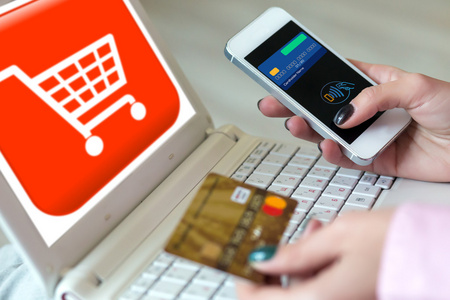 手中持有的女人信用卡和电话购物车 照片