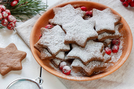 传统圣诞姜饼，星星在盘子上糖粉。红罗文分支云杉的浆果