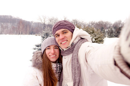 幸福的夫妇在冬天约会在公园做自拍照