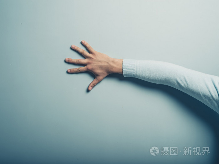 男性的手抚摸着蓝色的墙