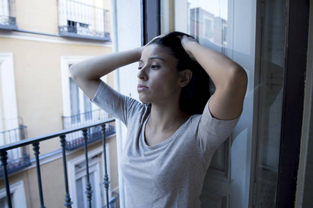 绝望的拉丁女人在家里阳台看摧残和压抑患上抑郁症