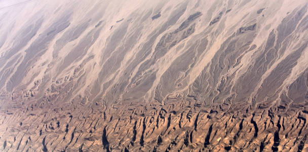 沙漠砂的新月形沙丘与棕色崎岖的地形