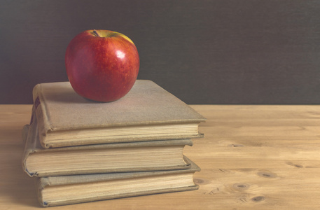 堆栈的书籍和木桌上的红苹果