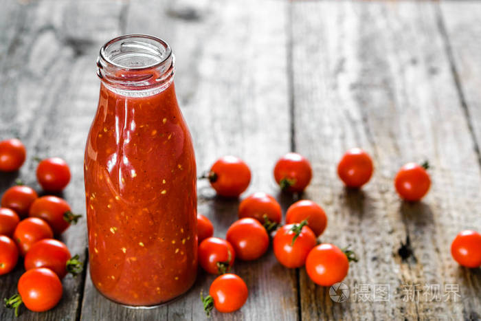 瓶番茄汁和新鲜的西红柿，在木制的背景下，有机健康食品的概念