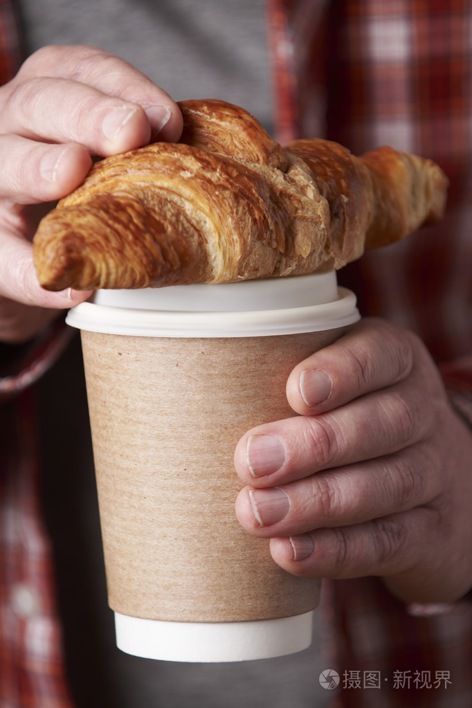 男人抱着外卖咖啡和牛角面包