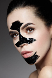 美容化妆品。女性与黑皮肤护理面膜在脸上
