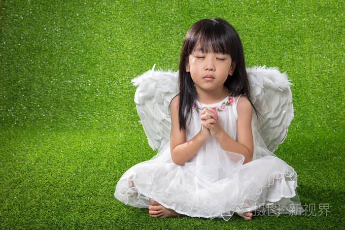 亚洲的中国小女孩,穿着天使翅膀和祈祷