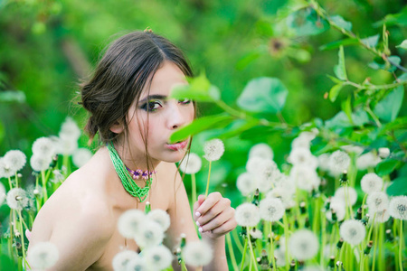 年轻女子与时尚化妆和珠在绿色的树叶