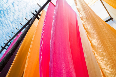 悬挂晾干后传统染色工艺的彩色织物照片