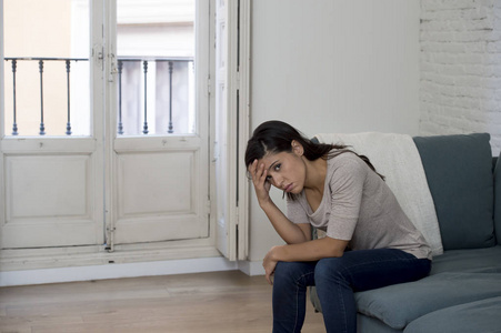 躺在家里坐在沙发上哭泣的拉丁女人担心痛苦抑郁感到悲伤照片