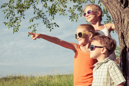 三个快乐的孩子们在附近树上玩耍照片