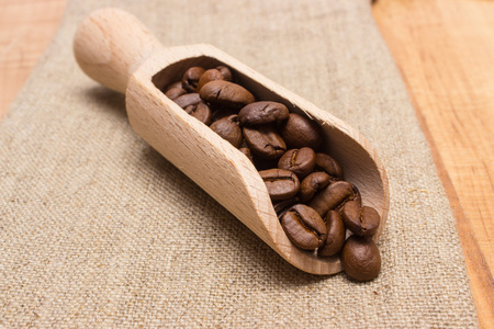 堆的咖啡豆与瓢对黄麻麻布上表图片
