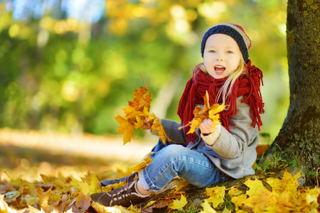 小女孩玩着秋天的树叶