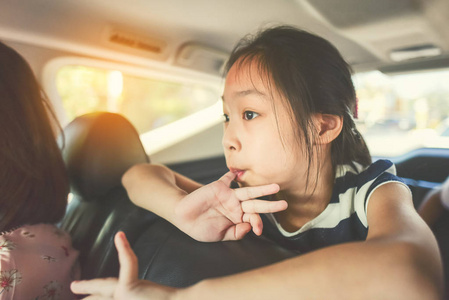 亚洲女孩坐在车里在旅行时，与她的家人