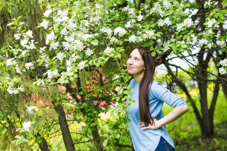 春黑发姑娘站在开花的树木室外的肖像