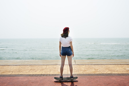 女孩骑滑板附近海