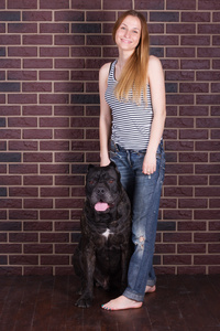 女孩站在墙附近和拥抱大狗