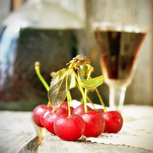 小眼镜和老式旧木背景上餐巾纸上的大瓶的樱桃酒