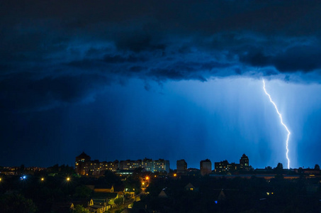 在夜空中城市上空的闪电击中房子的屋顶照片