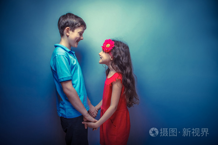 十几岁的女孩,抱着双手十几岁的男孩,在灰色的背景上复古 p