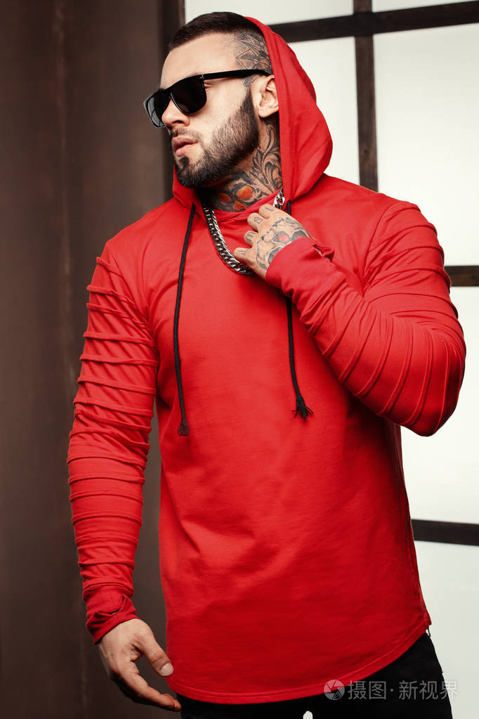 优雅帅气男模特搭配时尚纹身和黑胡子站和模型试验或趋势时装杂志摆