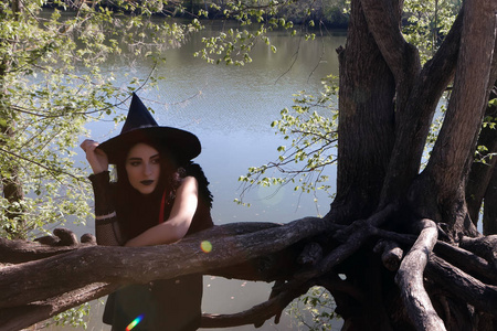 年轻女孩在女巫服装在树的根部