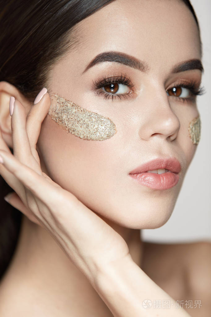 女人的脸部皮肤护理.美丽的女孩,用化妆品磨砂面膜