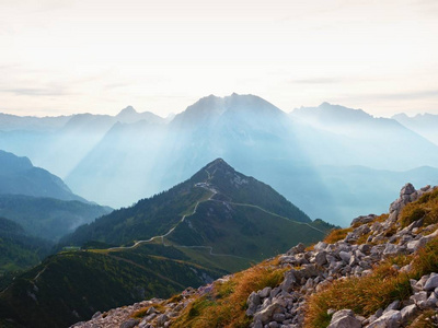 查看在高山悬崖和山谷。太阳在地平线上，蓝色天空与少云。阿尔卑斯山