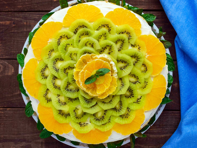 明亮的圆节日水果蛋糕装饰着猕猴桃 橘子 薄荷