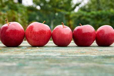 五个红色多汁苹果木绿色棕色岁的纹理背景上关闭。苹果上模糊的自然背景